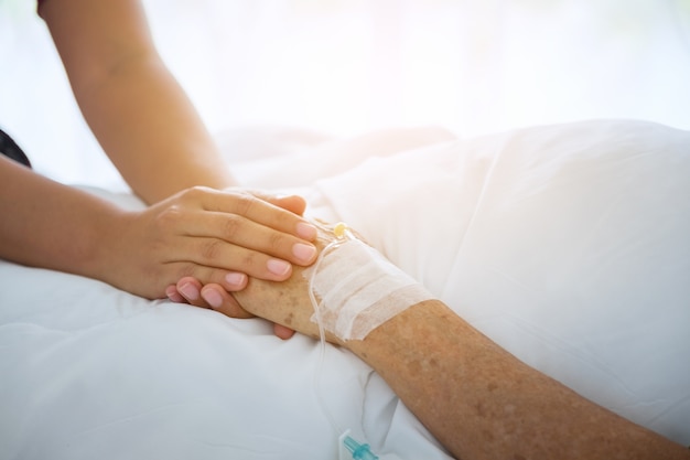 medical doctor holing senior patient's hands and comforting her