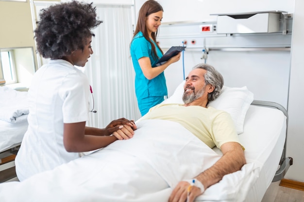 Medical doctor or nurse holding senior patients hands and comforting him