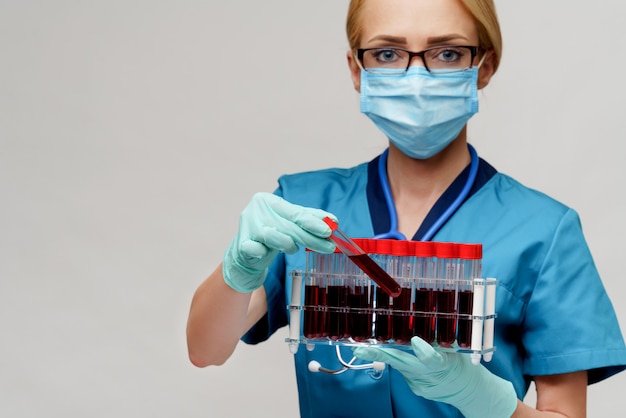 Врач медсестра женщина носить защитную маску и перчатки - держит стойку с вирусами крови