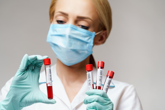 바이러스 혈액 검사를 들고 보호 마스크와 장갑을 착용 의사 간호사 여자