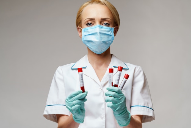Foto donna dell'infermiere di medico che indossa maschera protettiva e guanti - analisi del sangue del virus della tenuta