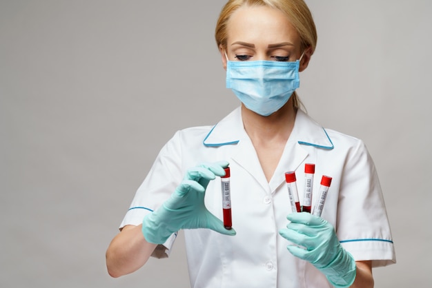 Photo medical doctor nurse woman wearing protective mask and gloves - holding virus blood test