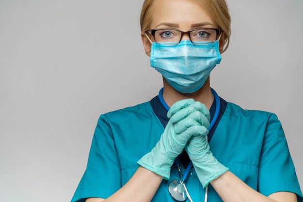 Medical doctor nurse woman wearing protective mask and latex gloves - praying nad hoping gesture