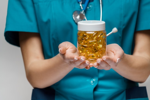 Medical doctor nurse woman wearing protective mask and rubber or latex gloves - holding can of pills