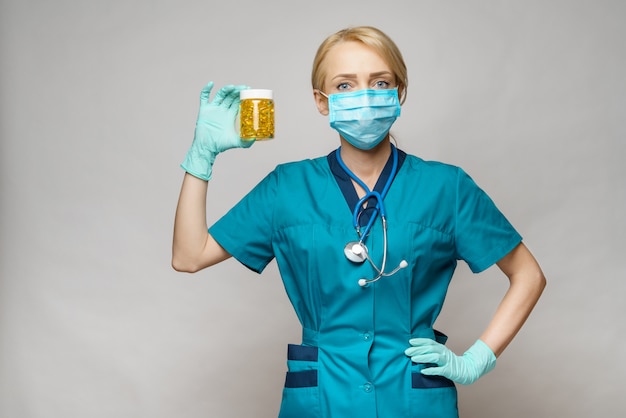 Medical doctor nurse woman wearing protective mask and rubber or latex gloves - holding can of pills