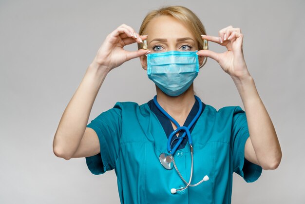 Medical doctor nurse woman wearing protective mask and rubber or latex gloves - holding pills