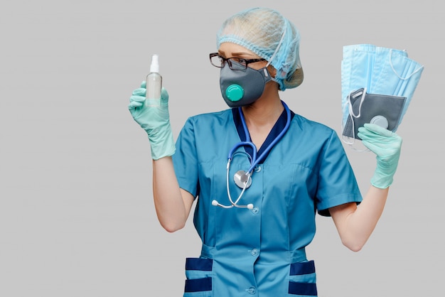 medical doctor nurse woman with stethoscope - holding protective mask and sanitizer