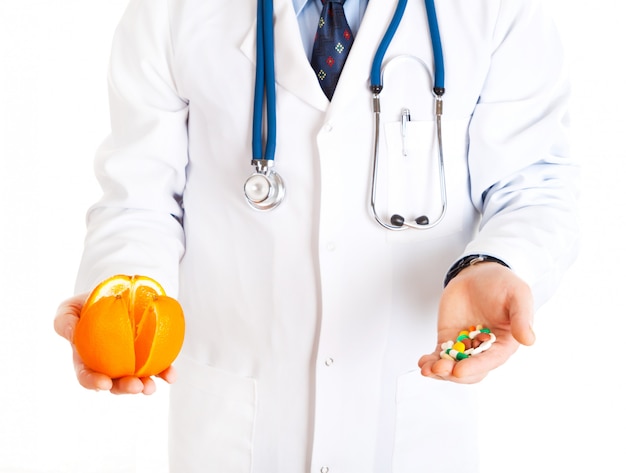 Medical doctor with pills in one hand and orange in other