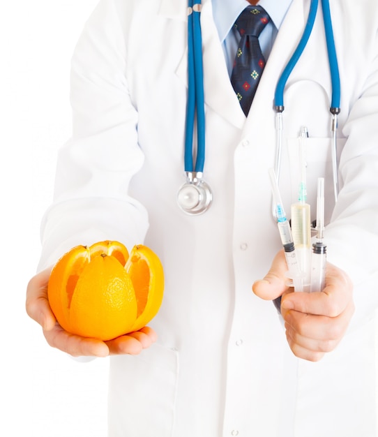 Medical doctor with pills in one hand and orange in other