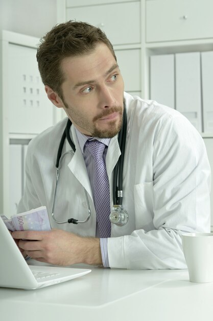 Medical doctor working with laptop and money in the office