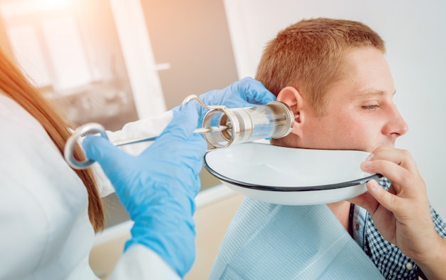 Photo medical ear washing with water in big syringe