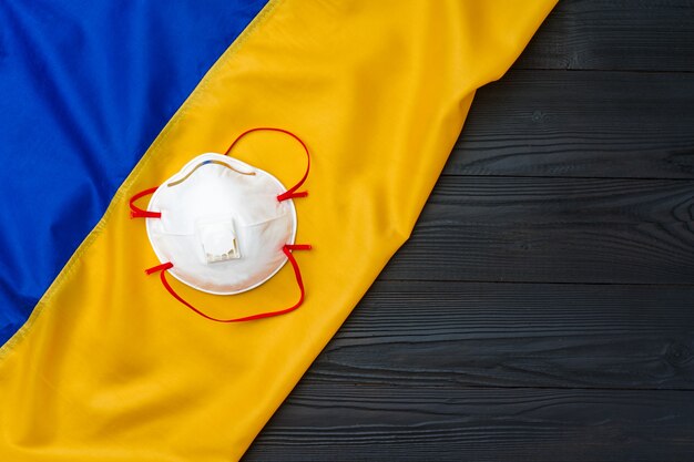 Medical face mask on the flag of Ukraine on wooden board