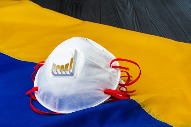 Medical face mask on the flag of Ukraine on wooden board