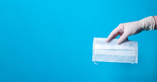 Photo medical face mask in hand on blue background. coronavirus protection concept. copy space