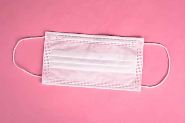 Medical gauze protective mask on a pink background.