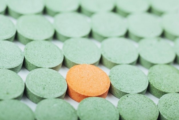 Медицинская зеленая и одна оранжевая таблетки для лечения и здравоохранения на белом фоне