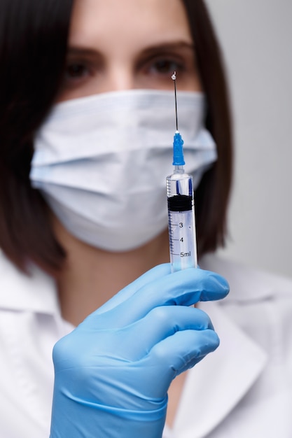 Iniezione medica, malattie, assistenza sanitaria, scienza, diabete. medico o infermiere in ospedale in possesso di una siringa con vaccini liquidi che si preparano a fare un'iniezione. attrezzature mediche. persone in uniforme bianca, vestaglia