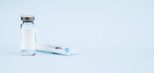 medical jar and syringe on blue surface with copy space