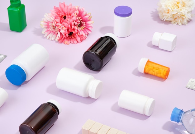 Medical jars of different colors and sizes are scattered on a purple background Concept of healthcare and medicine Pills capsules and tablets