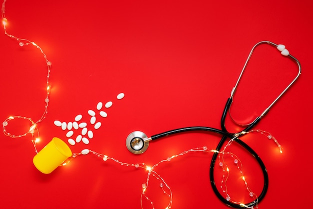 Medical layout on a red background with a beautiful garland of a stethoscope a christmas tree made of pills. merry christmas concept for doctors and medical clinics