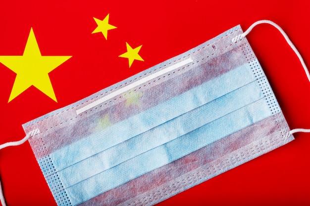 Medical mask on the background of the Chinese flag. Disposable face masks for viruses, Coronavirus.