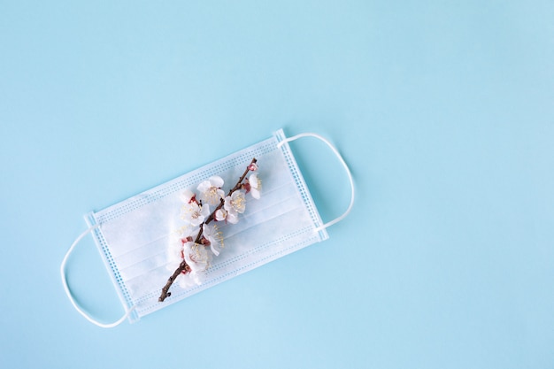 Medical mask and branch of spring flowers