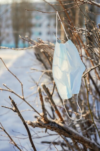 Medical mask on a branch in winter. Symbol of 2020