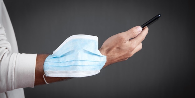 Medical mask in hand using mobile phone