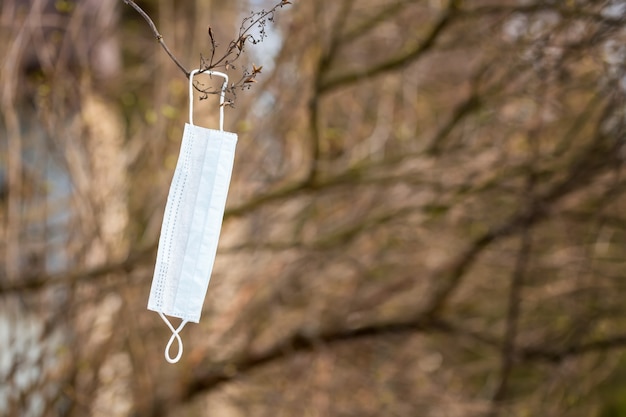 Medical mask hanging on a tree branch