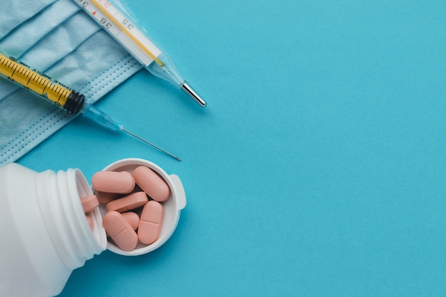 Medical mask, jar of pills, syringe and thermometer