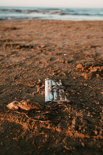 Medical mask lying on the sand of the Mediterranean beach.