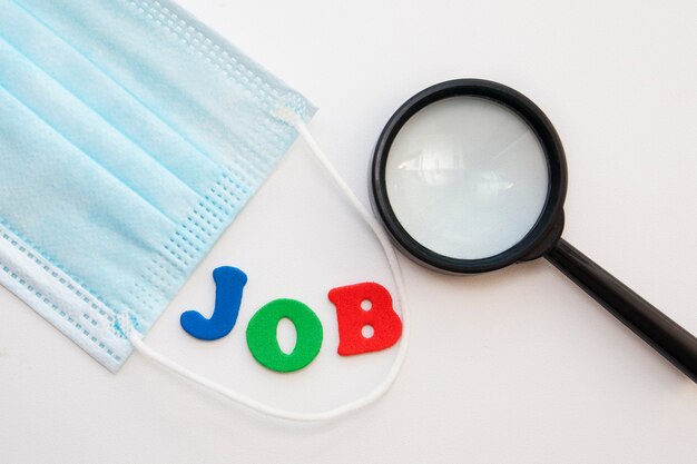 Medical mask and a magnifying glass near the word job done with letters