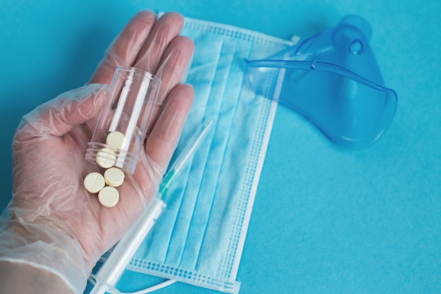 Medical mask syringe and tablets close on the blue background