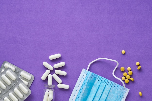 Medical mask with various pills on lilac