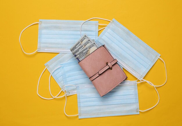 Medical masks and wallet with money on yellow background