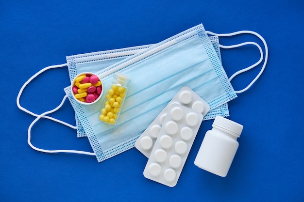 Medical masks with different pills on a blue background