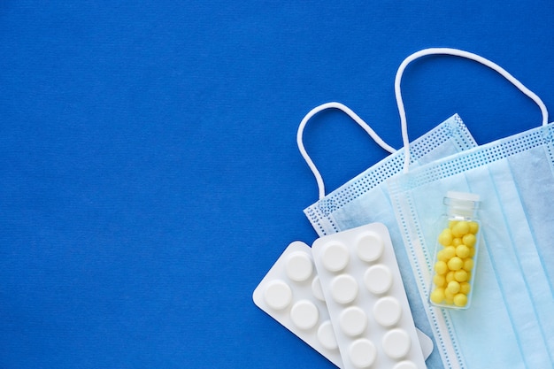 Medical masks with different pills on a blue background