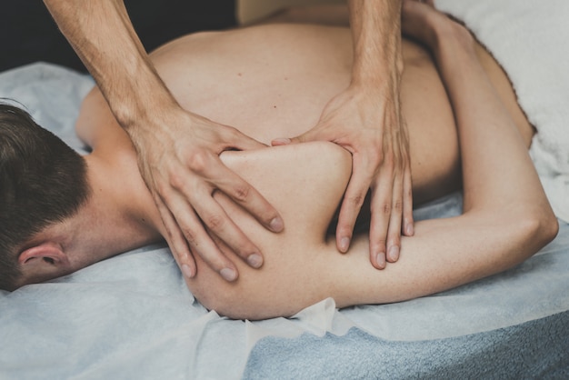 Medical massage of the spine. Masseur massages a teenager in a clinic