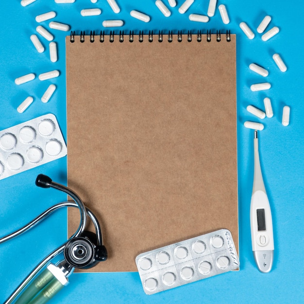 Photo medical mockup notepad with stethoscope pills and thermometer top view space for text