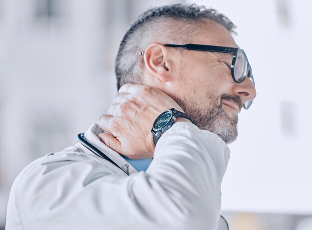 Medical neck pain or optometry and a doctor in his office with an injury while feeling stress Healthcare burnout or accident with a mature optician holding his spine or shoulder in a clinic