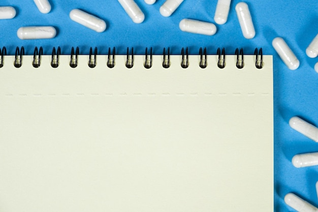 Medical notepad with pills on a blue background space for text