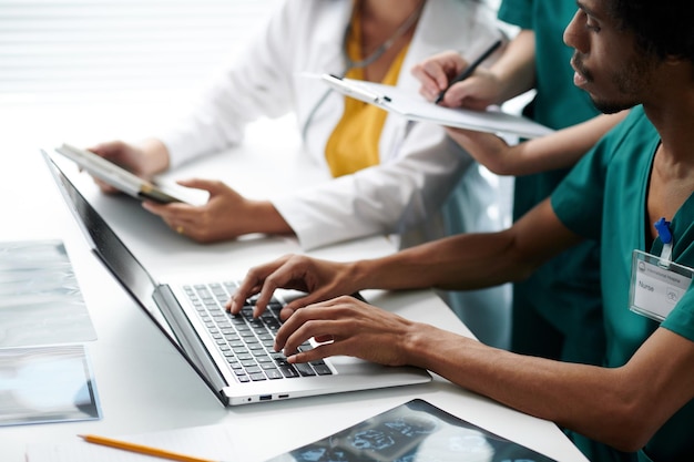 Photo medical nurse filling document on laptop entering information on medical tests results