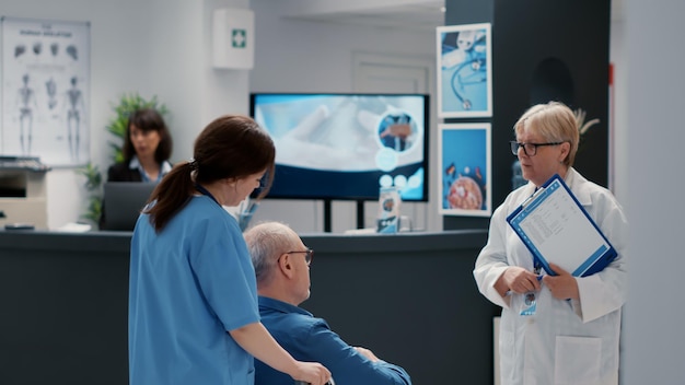 Medical nurse helping senior man with disability to chat with old doctor