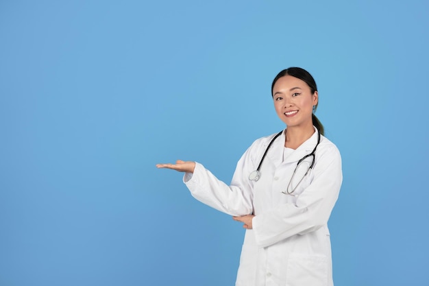 Photo medical offer asian female physician pointing aside at copy space with palm