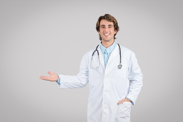 Medical offer concept happy young male physician pointing aside and showing free space with open