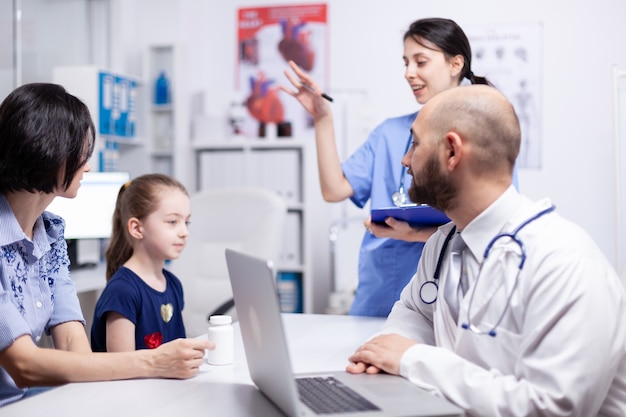 Medical personal during consultation of little girl in hospital office. Healthcare physician specialist in medicine providing health care services treatment examination.