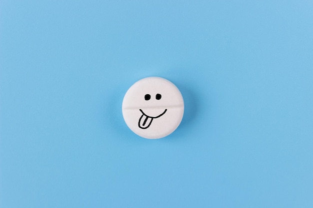 Medical pill with a cheerful face on a blue background Health support