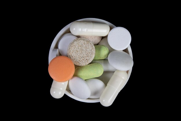 Медицинские таблетки и антибиотики на черном столе. Вид сверху
