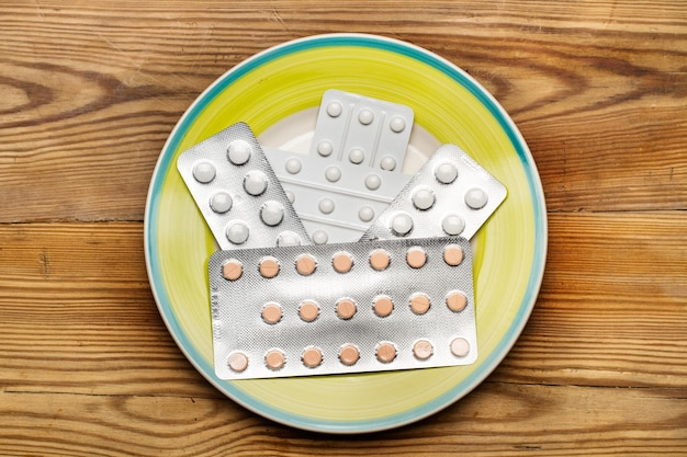 Medical pills in blister pack on a plate on a wooden table