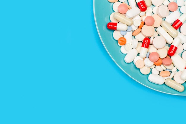 Medical pills and capsules in a blue plate on a blue background